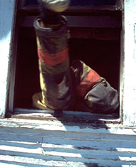 Firefighter climbing through window during training fire