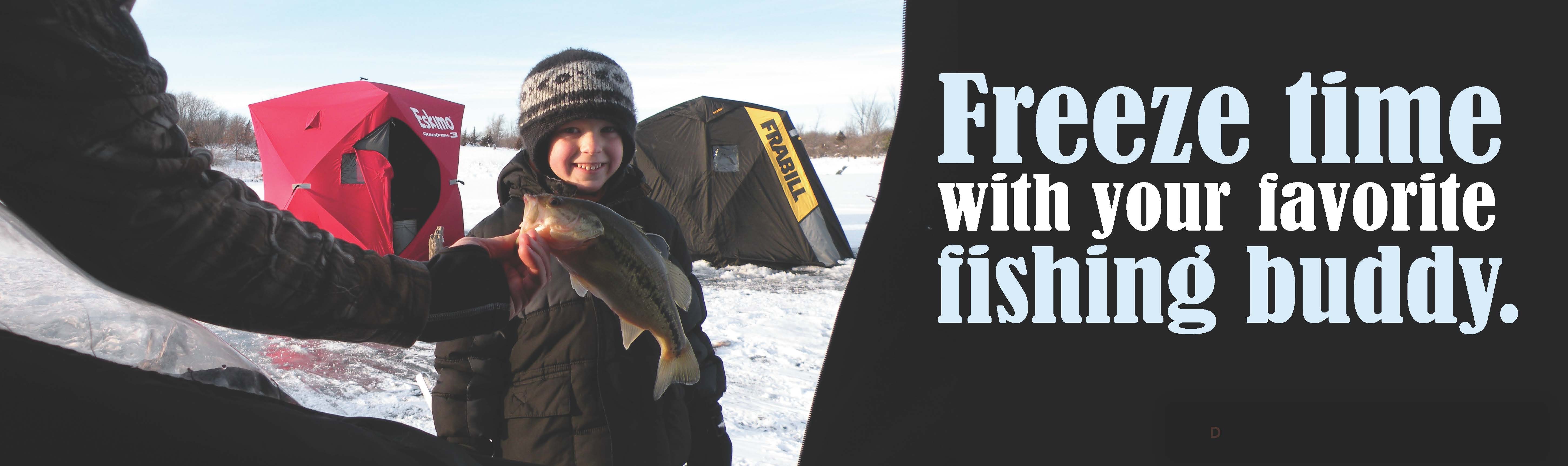 a young boy standing outside an ice fishing shack with a fish.