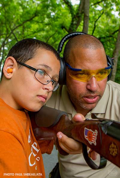 adult showing child how to sight a gun