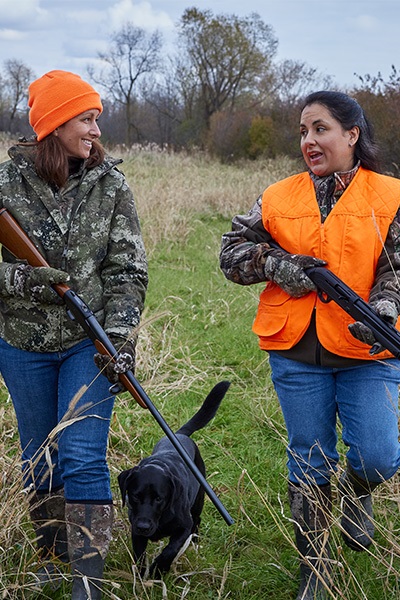 two female hunters walking with dog seeking rabbits