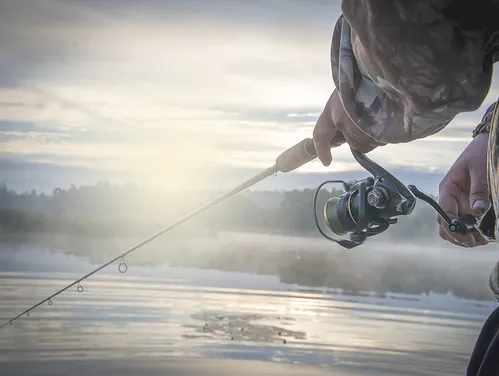 A fisherman with his line cast and a hazy morning mist.