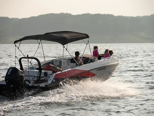 A family boats across a lake at the end of a summer day.