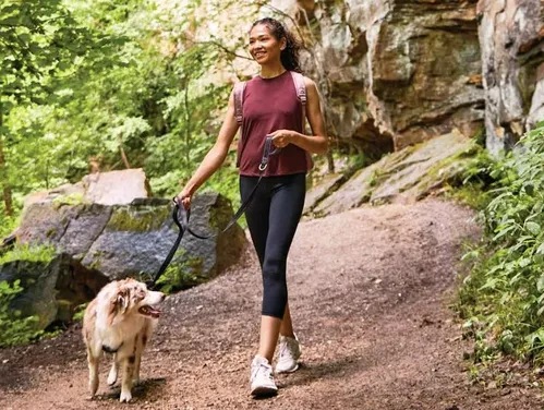 Woman walking her dog on a hiking trail.