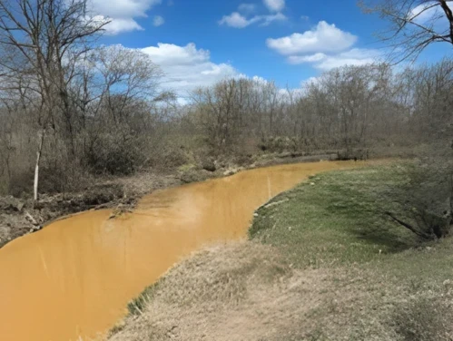 This image shows brown, murky water flowing at the South Branch of Lizard Creek in Fort Dodge