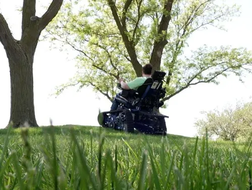 Person using an accessible chair to go up a hill.