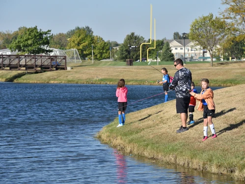 Kids and an adult fishing at a community fishing pond