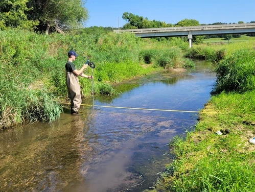 This image shows a seasonal Environmental Monitoring Field Technician conducting surveys at a monitoring site.