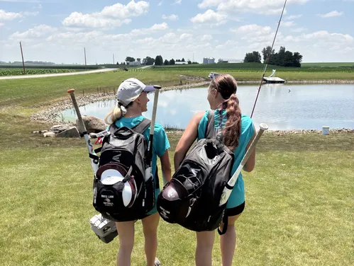 Two high school girls softball players on their way to a local pond to fish