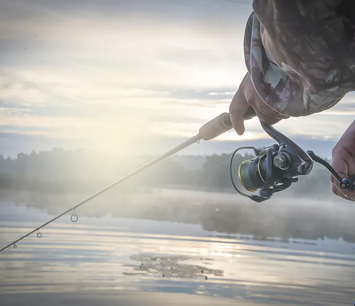 A fisherman with his line cast and a hazy morning mist.