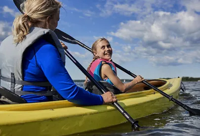 Two girls paddling in a yellow kayak 