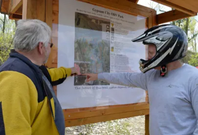 Front kiosk for Gypsum City OHV park, showing two men pointing at the map.