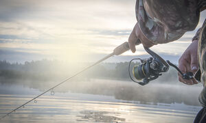 A fisherman with his line cast and a hazy morning mist.
