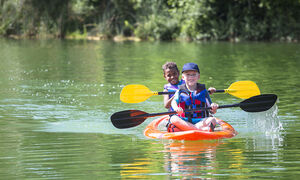 A red kayak with two paddlers on the water.