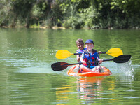 A red kayak with two paddlers on the water.