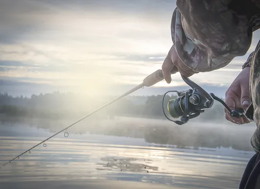 A fisherman with his line cast and a hazy morning mist.