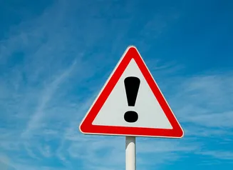 Triangular warning sign with red border and an exclamation point in the center.