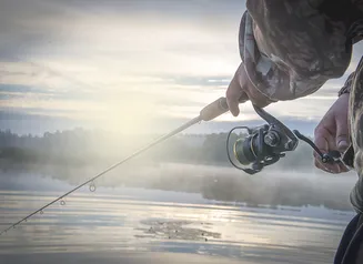 A fisherman with his line cast and a hazy morning mist.