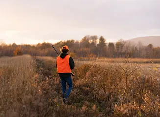 Hunter walking a field in the fall.