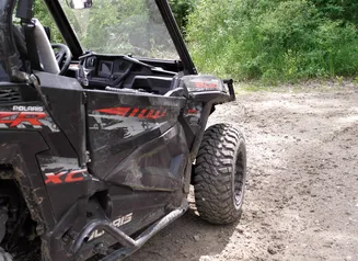 Close up of an off-highway vehicle parked on a dirt trail.