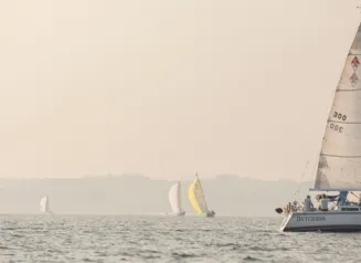 A photo of a large body of water with short, choppy waves and a sailboat.