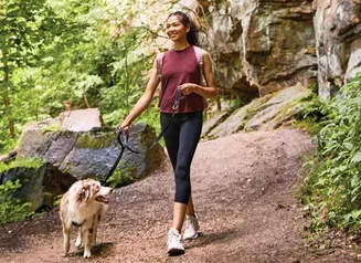 Woman walking her dog on a hiking trail.