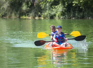 A red kayak with two paddlers on the water.