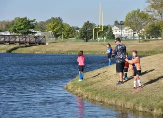 Kids and an adult fishing at a community fishing pond