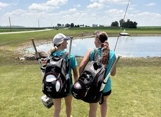 Two high school girls softball players on their way to a local pond to fish