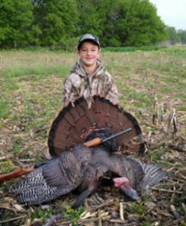 Logan Luft poses in front of a hunted turkey