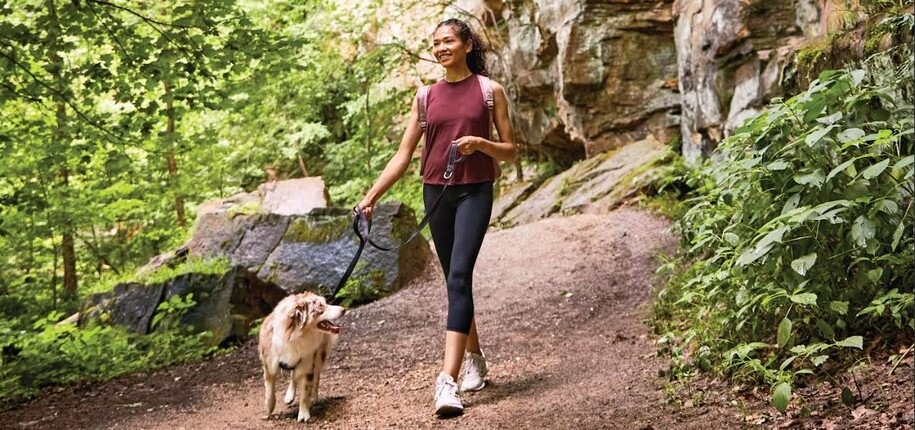 Woman walking her dog on a hiking trail.