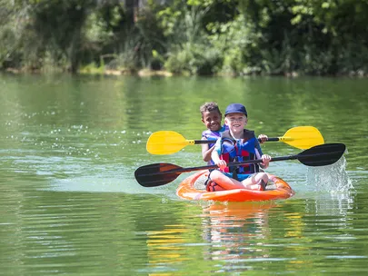 A red kayak with two paddlers on the water.